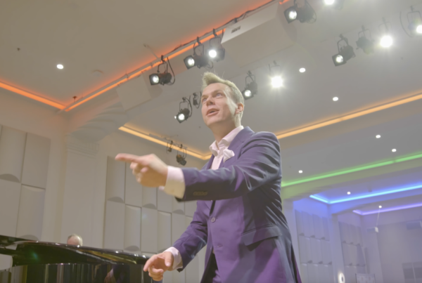 Jacob Stensberg conducts looking upwards on stage at The Chan National Queer Arts Center.